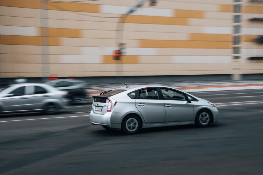 A driver in a third-generation Toyota Prius drives quickly on a city street.