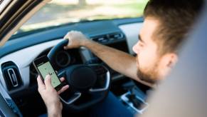 An Uber driver on their smartphone in a parked car.