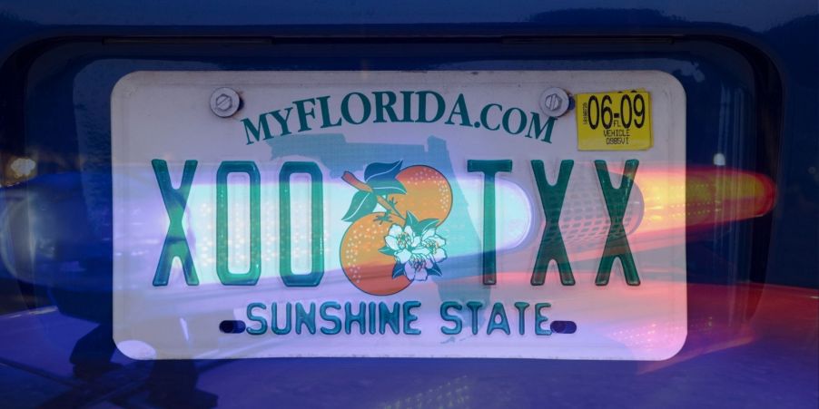 A Florida license plate with an overlaying semi-transparent image of police lights on over it