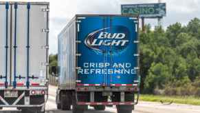 A Budweiser beer semi truck driving away from viewer in right highway lane