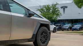 A Tesla Cybertruck parked at a Tesla dealership with different Tesla models in the background