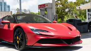 A red Ferrari SF90 Stradale convertible parked at a gas station in close right front angle view