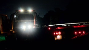 A tow truck bed illuminated by bed lights at night