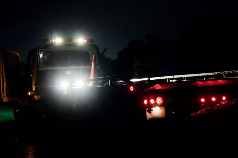 A tow truck bed illuminated by bed lights at night