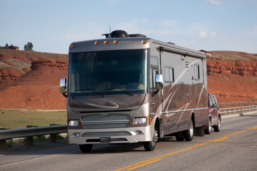 An RV on the road towing an SUV