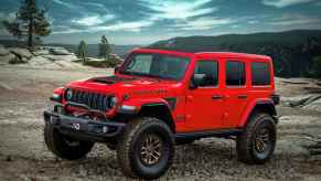 A red Jeep Wrangler Rubicon sits on a gravel road of a mountain