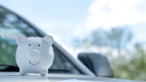 A white piggy bank on a silver car hood