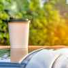 A pumpkin spice latte cup on a car roof in close view