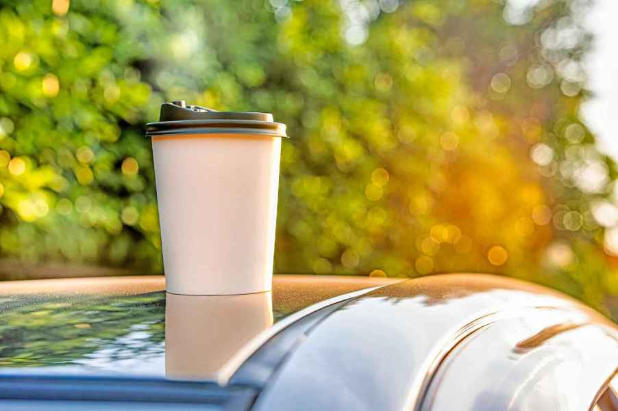 A pumpkin spice latte cup on a car roof in close view