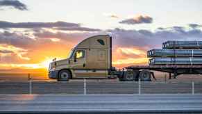 A semi-truck parked in left profile view with a steel rod load