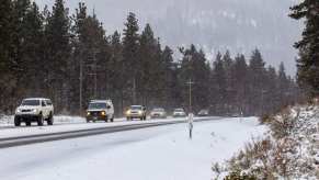 Cars driving on a snowy mountain highway during snowfall