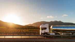 A tanker truck hauling wine drives down a road in front of a vineyard