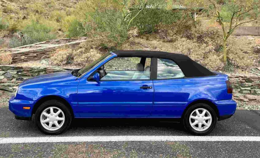 A bright blue 1998 VW Cabrio two-door convertible parked outside in full left profile view