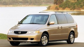 A gold metallic colored 2002 Honda Odyssey parked in front of water in left front angle view