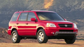 A red 2003 Honda Pilot parked outside in right front angle view