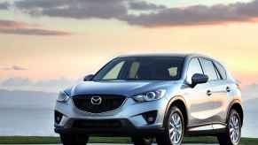 A silver 2014 Mazda CX-5 parked outside in left front angle view at dusk