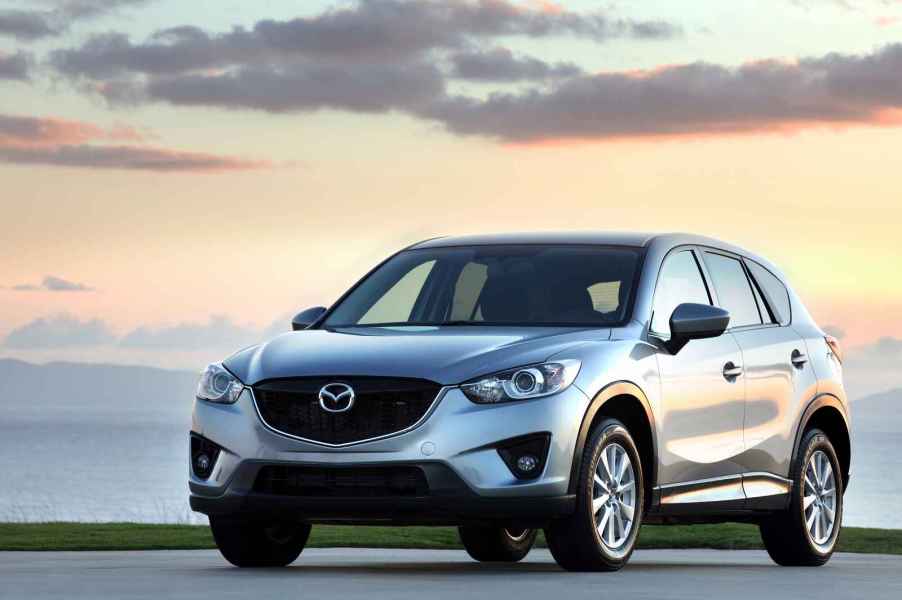 A silver 2014 Mazda CX-5 parked outside in left front angle view at dusk