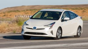 A white 2016 Toyota Prius driving in left front angle view