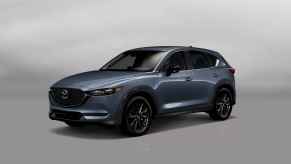 A blue-grey 2021 Mazda CX-5 SUV parked in left front angle view on white floor and background