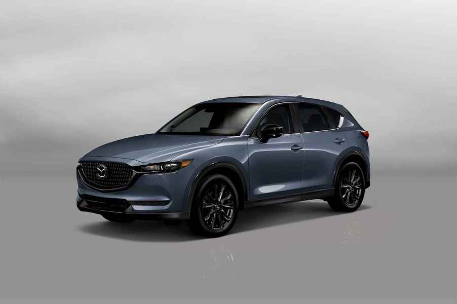 A blue-grey 2021 Mazda CX-5 SUV parked in left front angle view on white floor and background