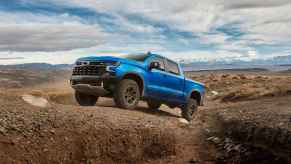 A blue 2024 Chevrolet Silverado pickup parked on a rocky hill in right side angle view