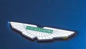 White Aston Martin badge on the blue exterior of a new car.