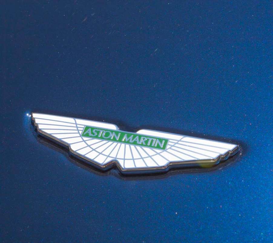 White Aston Martin badge on the blue exterior of a new car.