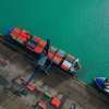 A cargo ship near another vessel at a large maritime port.