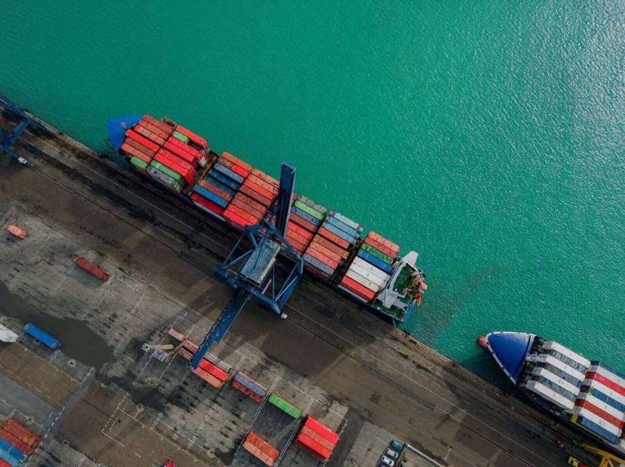 A cargo ship near another vessel at a large maritime port.