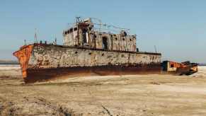 Scrapped ship, dismantled on a beach, the sea in the background.