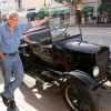 Jay Leno leans against a classic car from his collection in downtown LA