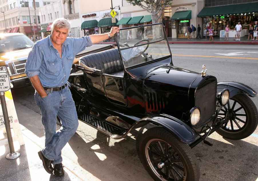 Jay Leno leans against a classic car from his collection in downtown LA