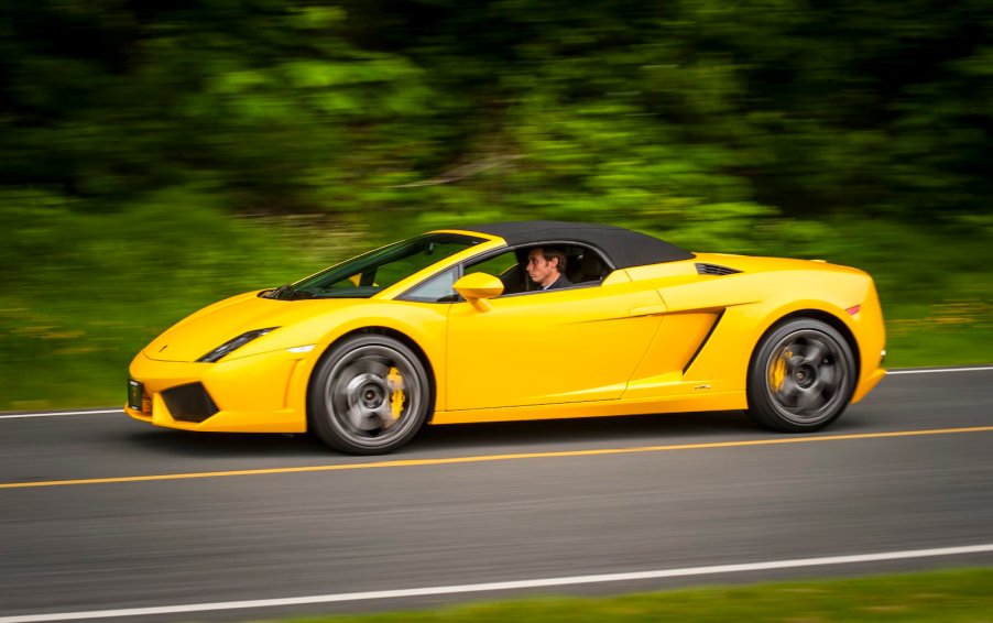 Young man driving a yellow Lamborghini convertible Gallardo.