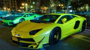 Lamborghini supercars parked at a luxury car show in Qatar, the city visible in the background.