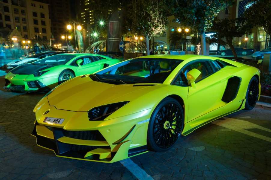 Lamborghini supercars parked at a luxury car show in Qatar, the city visible in the background.