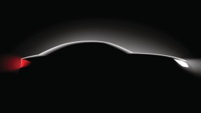 The silhouette of a luxury car, in front of a black background.