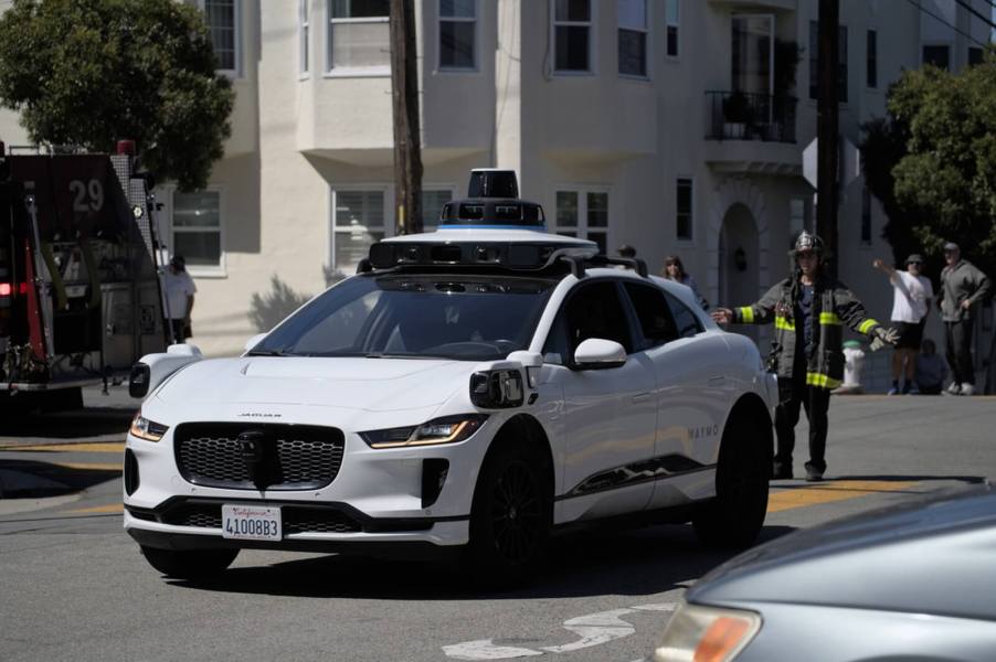 A Waymo self-driving car at an emergency scene with firefighters.