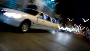 White limousine blurs by at night.