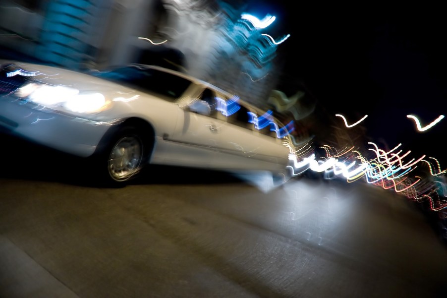 White limousine blurs by at night.