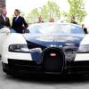 Men in suits stand next to a black and white Bugatti Veyron supercar.