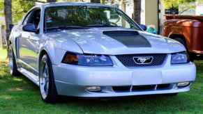 A silver 2001 Ford Mustang GT sitting on a lawn at a car show