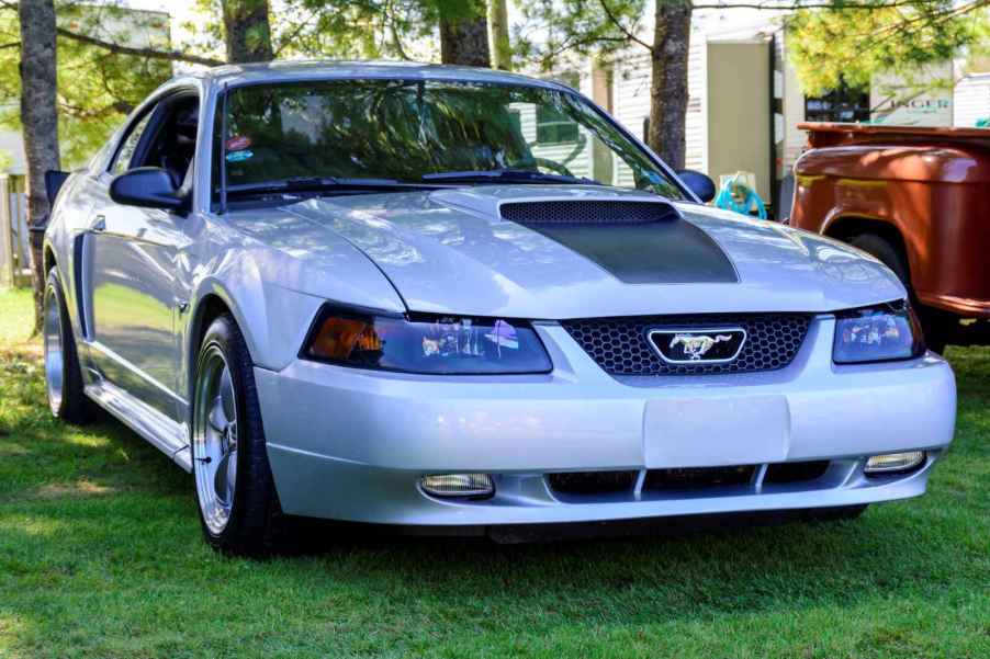 A silver 2001 Ford Mustang GT sitting on a lawn at a car show