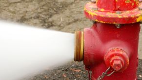 An open fire hydrant gushing water onto a street