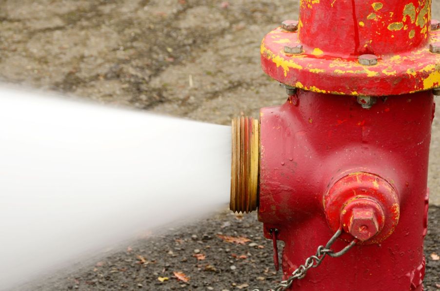 An open fire hydrant gushing water onto a street