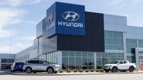 The exterior of a Hyundai dealership, with three cars sitting outside of the building