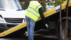 A man loading a van onto a tow truck