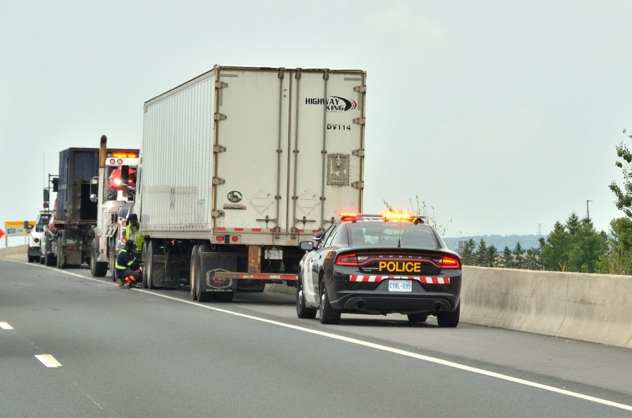 A police car behind a semi-truck