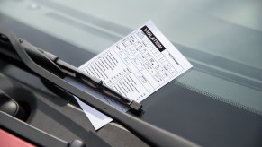 A parking ticket pinned onto a car's windshield by a windshield wiper