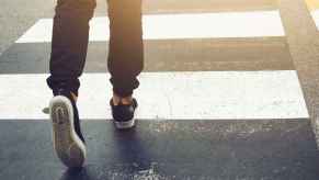 A pedestrian crossing the street using a crosswalk legs only shown