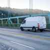 A white van traveling down a scenic driveway